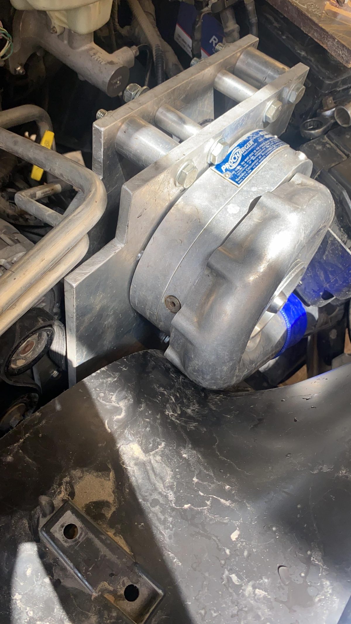 Clean front view of the installed ProCharger and bracket with the inner fender visible.